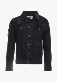Veste en denim noire avec détails usés, fermeture à boutons sur le devant, poches poitrine et col classique. Tissu texturé.