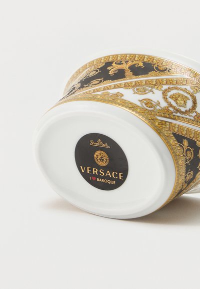 Λευκό πορσελάνινο φλιτζάνι με μαύρο και χρυσό μπαρόκ σχέδιο, ακουμπισμένο στο πλάι, με την επωνυμία Versace και το λογότυπο Rosenthal στη βάση.