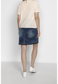 Ljusrosa kortärmad topp med vertikala ränder; blå denimkjol med urtvätt och fem fickor; vita sneakers.