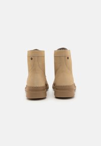 Bottes chelsea beiges en suède lisse, avec un bout arrondi et une semelle en caoutchouc. Présente un minimum de coutures et un petit logo près du talon.