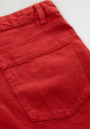 Red corduroy fabric with distinct ribbed texture and a back pocket, featuring visible stitching and a belt loop at the waist.