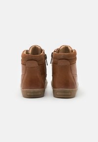 Bottines en cuir marron avec un col en daim doux, des fermetures éclair sur le côté et une semelle en caoutchouc beige, présentant un design simple et une texture lisse.