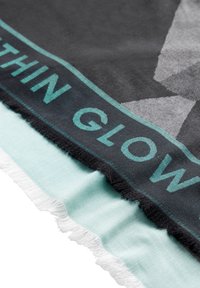 Gran bufanda negra con un diseño geométrico, que presenta texto en color teal que dice "THIN GLOW". Los bordes tienen una textura deshilachada; el lado inferior es de un verde menta claro.