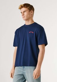 Μπλε σκούρο βαμβακερό T-shirt με κοντά μανίκια και στρογγυλή λαιμόκοψη, με το κόκκινο λογότυπο "Pepe Jeans" κεντημένο στο στήθος. Απλός σχεδιασμός.