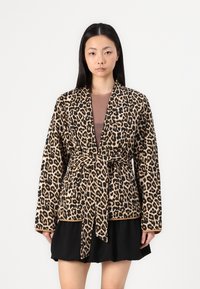 Leopard print robe, soft fabric, long sleeves, belted waist, open front, tan and black pattern, relaxed fit, paired with a black skirt.