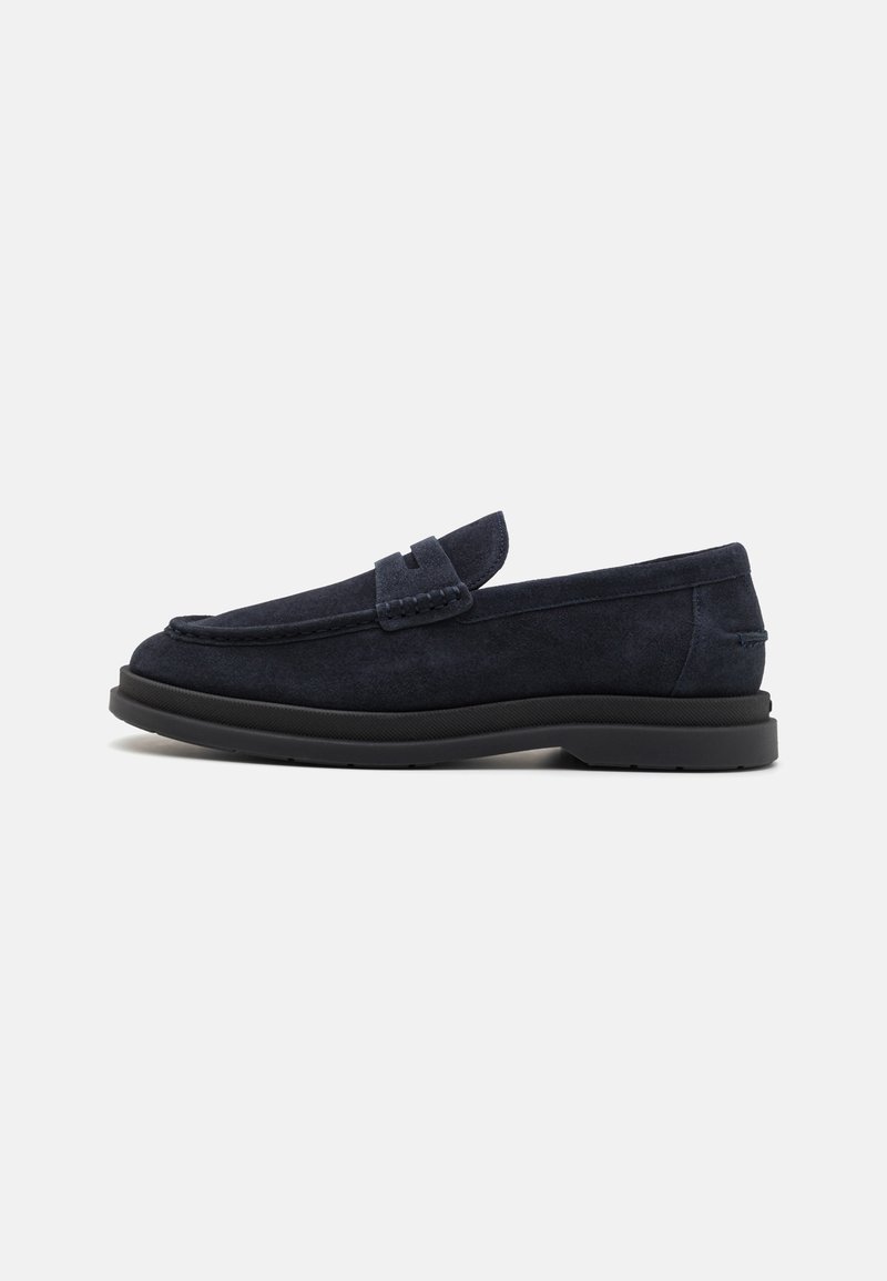 Tamsiai mėlyni suede loaferiai su apvaliu pirštu, siūlėtais akcentais ir žemu juodu guminiu padu. Švarus, minimalistinis dizainas be matomų logotipų.