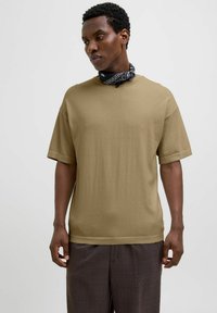 Khaki bomulds t-shirt med korte ærmer, afslappet pasform, rund halsudskæring og et sort mønstret tørklæde bundet om halsen. Struktureret stof.