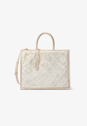 Quilted white faux fur tote bag with beige leather trim, top handles, detachable shoulder strap, and tag with branding detail.