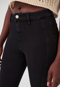 Zwarte high-waisted jeans van denim, met een knoopsluiting bij de taille en zijzakken, met een slank, aansluitend ontwerp.