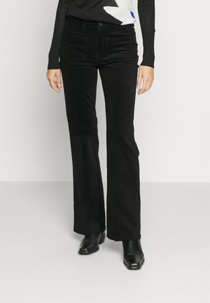 Black flared pants made from soft fabric, featuring a smooth texture, front pockets, and a fitted waist. Worn with a black patterned top.