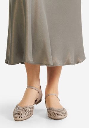 Béžové baleríny s perforovaným vzorem a vlnitými okraji. Mají úzký pásek kolem kotníku a zaoblenou špičku.