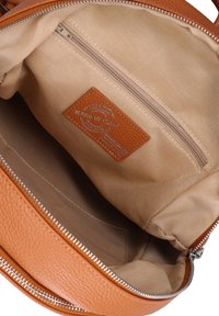 Interno della borsa in pelle tan con rivestimento in tessuto beige, tasca con zip interna e etichetta con la scritta "Fatto in Italia".