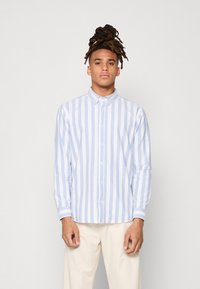 Camisa a rayas azul claro y blanca con cuello tipo abotonado, manga larga y dobladillo recto. La tela parece suave y ligera.