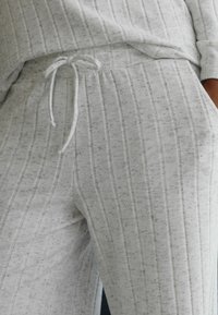 Hellgraue Jogginghose aus weichem, strukturiertem Material, mit vertikalen Streifen und einem Kordelzugbund. Bequeme und lässige Passform.