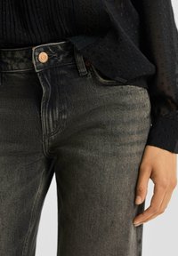 Zwarte denim spijkerbroek met een taillehoogte en een rechte pijp. Voorzien van een koperen knoop, subtiele vervaging en een gladde textuur. Afgewerkt met zwarte stiksels.