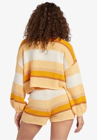 Brede gebreide trui en short set in oranje, geel en witte strepen. De trui heeft een cropped ontwerp en een ontspannen pasvorm van de mouwen; zachte textuur overal.