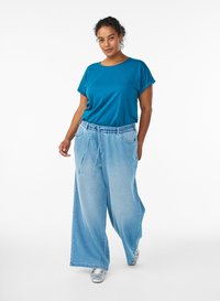 Teal short-sleeve shirt paired with light blue, wide-leg denim pants. Pants feature a drawstring waist and two front pockets. Silver shoes.