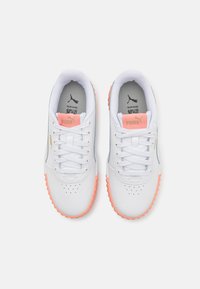 White sneakers feature a smooth leather upper, pink accents on the tongue and outsole, and perforated detailing on the toe.