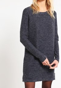 Dark grey knit sweater dress with long sleeves, round neckline, side slits, and a textured finish. Soft material with slight stretch.