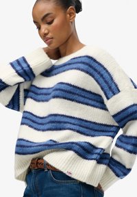 Gestrickter Pullover mit blauen und weißen horizontalen Streifen, weiten Ärmeln und einem gerippten Saum. Weiche Textur, entspannte Passform und lässiger Stil.