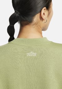 Sweatshirt en tricot vert olive avec un col rond ; doté d'un logo "nike" brodé en blanc au dos, de manches courtes et d'un tissu texturé.