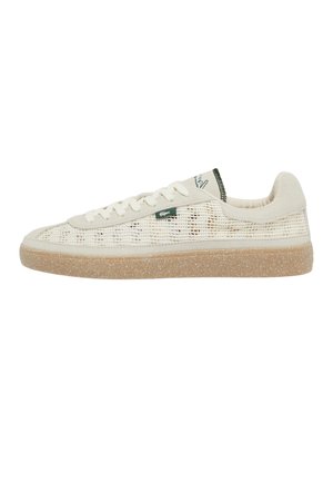 Beige lage sneaker met mesh zijkanten, witte veters, lichtbruine textuurzool en een klein groen logo-label aan de zijkant.