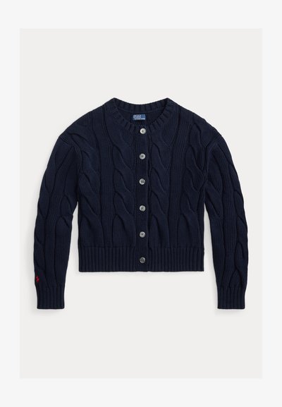 Καρντιγκάν σε ναυτικό μπλε με πλέξη καλώδιο, στρογγυλή λαιμόκοψη, ριμπ μανσέτες και τελείωμα, με ασημένια κουμπιά και μικρό κόκκινο λογότυπο στο μανίκι.