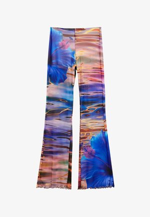 Legíny s živým potiskem velkých modrých ibišků na barevném vzoru odrážející se vodní hladiny.