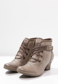 Hnědé kožené kotníkové boty s šněrovacím designem, kulatou špičkou, bočním detailem s přezkou a puntíkovými výseky na podpatku.
