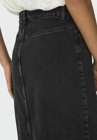 Zwarte denim rok met een hoge taille, met een donkere wassing, zichtbare stiksels en een rechte pasvorm. De achterkant benadrukt de naaddetails.