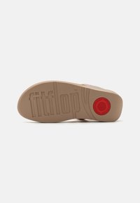 Sole in gomma beige con superficie testurizzata, logo "fitflop" incastonato, accento circolare rosso e motivo di ammortizzazione visibile.