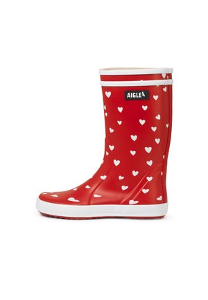 Bota de lluvia de goma roja con patrón de corazones blancos, ribete y suela blancos, y logo rectangular negro "Aigle" cerca de la parte superior.