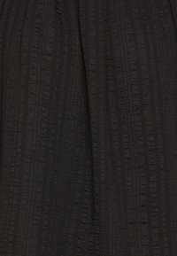 Tissu noir avec des rayures verticales texturées et lisses créant un motif subtil et de légers plis dans le matériau.