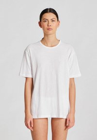 Biele oversized tričko s okrúhlym výstrihom a krátkymi rukávmi. Vyrobené z mäkkého, ľahkého materiálu s jemnou textúrou.