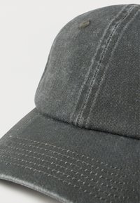 Kandatud must denimist pesapallo soki, millel on nähtavad õmblused ja kangatekstuuri, valgel taustal.