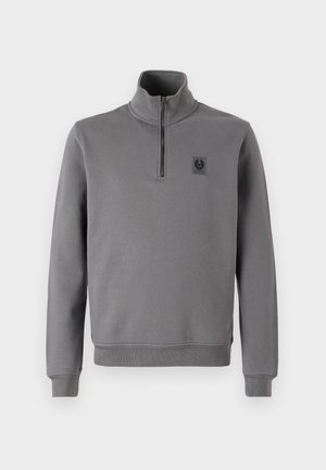 Sudadera gris de pullover con cuello alto, cremallera frontal de media longitud, puños y dobladillo de canalé, y un pequeño parche con el logo en el pecho. Textura de tela suave.