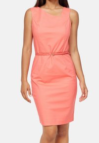 Korálové šaty s přiléhavým střihem, výstřihem do kulata, bez rukávů, s páskem v pase a kulatou sponou, vyrobené z hladké tkaniny.