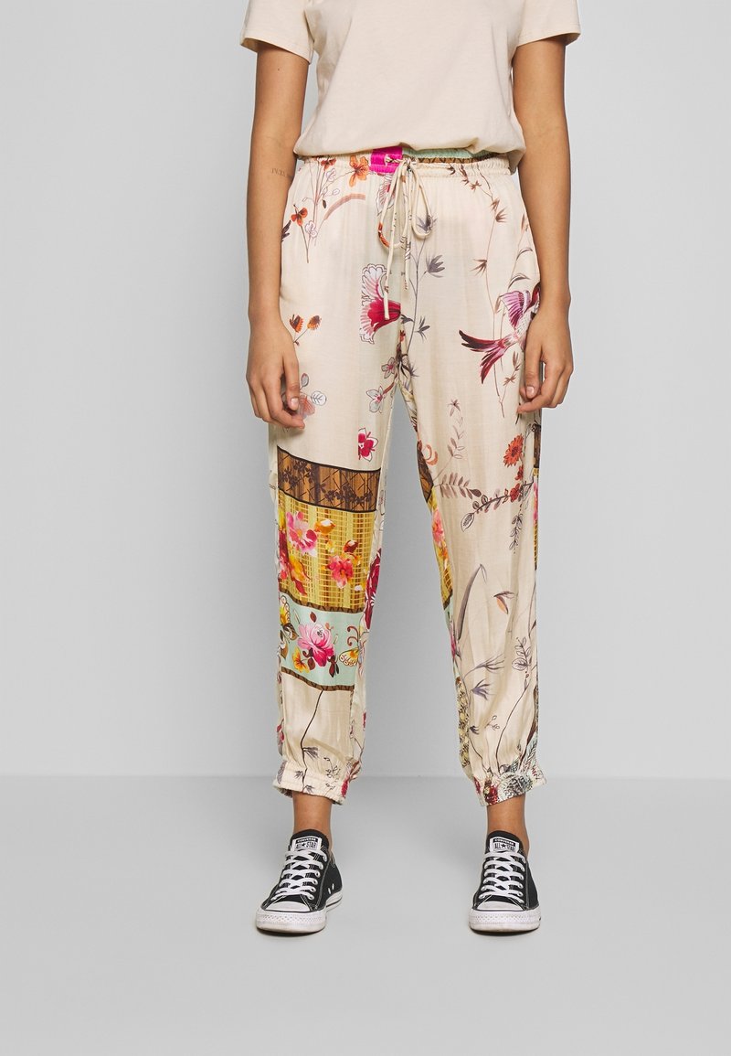 Blommönstrade, lätta byxor i krämfärgad nyans, med elastisk midja och muddar, prydda med olika livfulla mönster på tyget.