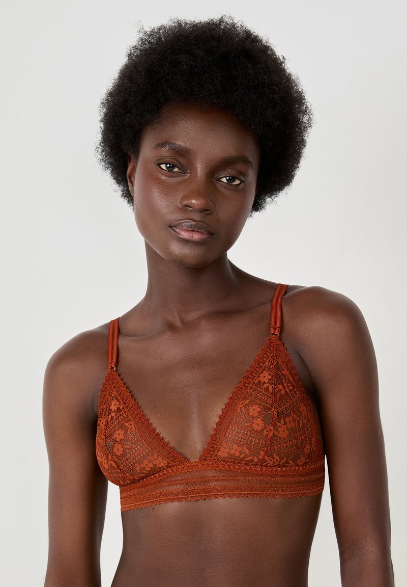 Bralette triangolare in pizzo arancione bruciato, caratterizzato da delicati motivi floreali, spalline regolabili e una morbida banda sottostante con dettagli a onde.