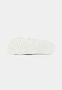 Λευκή εσωτερική σόλα παπουτσ�ιού με υφή, στρογγυλεμένο σχήμα και κυκλικά σημεία πρόσφυσης. Διαθέτει λογότυπο ανάγλυφο κοντά στη φτέρνα.