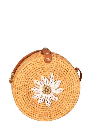 Ronde geweven rieten tas met een tan leren schouderband en een witte bloemdecoratie met gouden kralen in het midden.