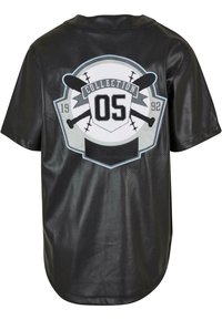 Sort kortærmet trøje lavet af perforeret stof med et cirkulært grafisk motiv med teksten "COLLECTION 05" og krydsede baseballbatte, 1992 detalje.
