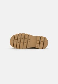 Sola de sapato de borracha castanha com sulcos profundos para tração, salto arredondado e superfície texturizada para aderência. Bordas suaves e cor uniforme por toda a superfície.