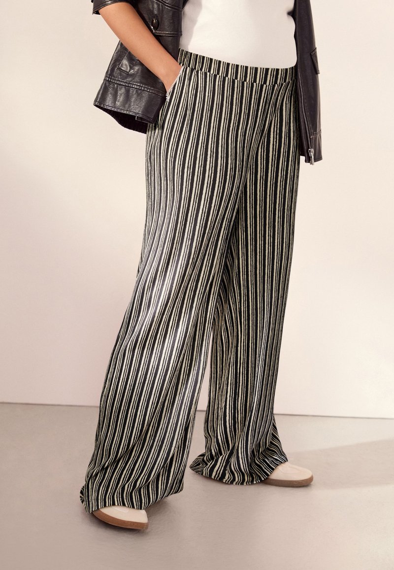 Pantaloni a gamba larga a strisce bianche e nere con una vestibilità rilassata, dotati di tasche laterali e una cintura comoda. Tessuto morbido e leggero.