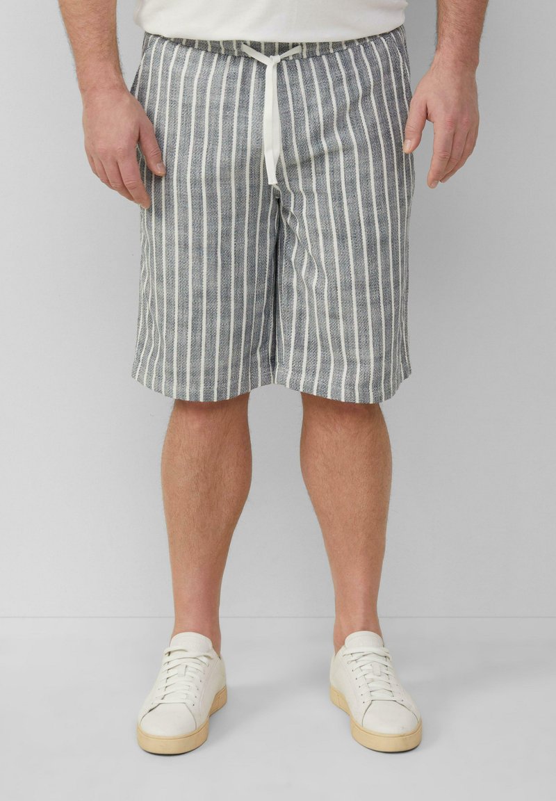 Shorts rayés en bleu et blanc, en mélange de coton, avec une taille à cordon de serrage et une coupe décontractée. Associés à des baskets blanches.