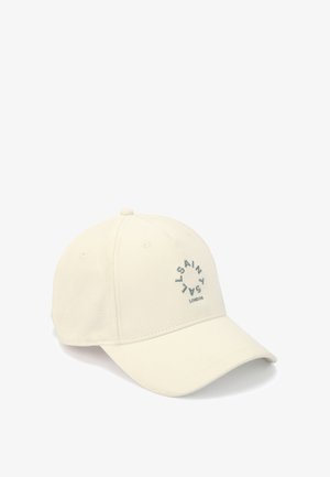 Gorra de béisbol beige hecha de algodón, con un logotipo bordado circular en gris, con visera curva y orificios de ventilación en la parte superior.