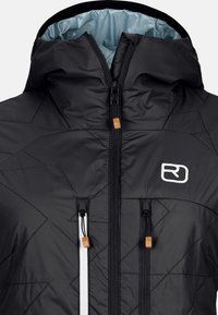 Schwarze isolierte Jacke mit einem Diamantmuster, zwei vorderen Reißverschlusstaschen, kontrastierendem weißen Reißverschluss, verstellbarer Kapuze und Logo auf der Brust.