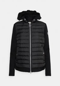 Giacca nera con cappuccio caratterizzata da una sezione anteriore trapuntata e imbottita, maniche lisce, chiusura con zip e dettagli con bottoni a pressione.