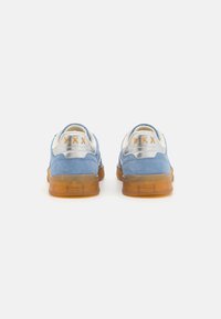 Blaue Wildleder-Sneaker mit einer weißen synthetischen Ferse und einer braunen durchsichtigen Gummisohle. Mit orangefarbenen Nähten am Fersenteil.