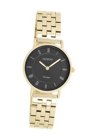 Montre en métal doré avec un cadran noir rond, des chiffres romains et un bracelet en maillons. Présente un design minimaliste et une texture lisse.